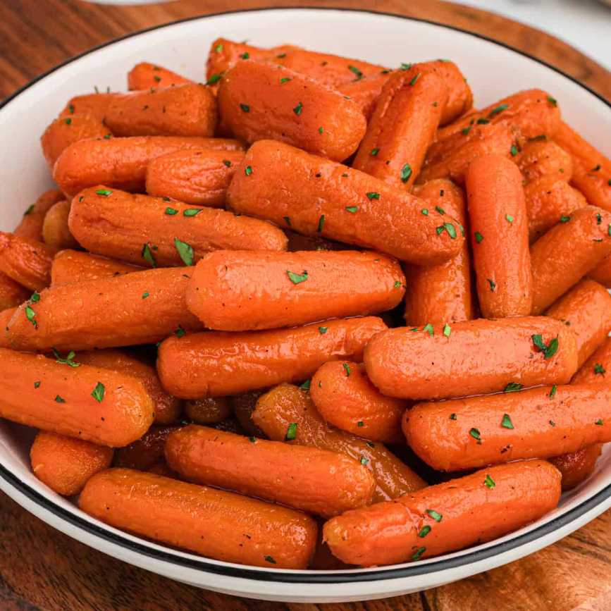 Glossy glazed baby carrots with a sweet and savory sauce and a sprinkle of sesame seeds